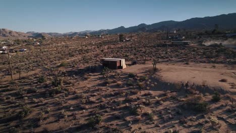 Ein-Abgelegenes-Kleines-Haus-Mitten-In-Der-Joshua-Tree-Wüste,-Während-Eine-Drohne-Davonfliegt