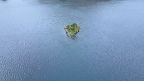 Acercándose-A-Una-Toma-De-Drones-De-Una-Pequeña-Isla-En-Medio-Del-Lago-Ullswater,-Un-Lago-Glacial-En-Cumbria,-Inglaterra-Y-Parte-Del-Parque-Nacional-Del-Distrito-De-Los-Lagos-En-El-Reino-Unido