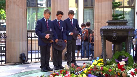 Tres-Jóvenes-Generaciones-De-Australianos-De-Pie-Frente-A-La-Llama-Eterna-En-El-Santuario-Del-Recuerdo-En-La-Plaza-Anzac,-Rindiendo-Homenaje-A-Quienes-Sirvieron-Y-Se-Sacrificaron-Durante-Los-Conflictos-De-Guerra.