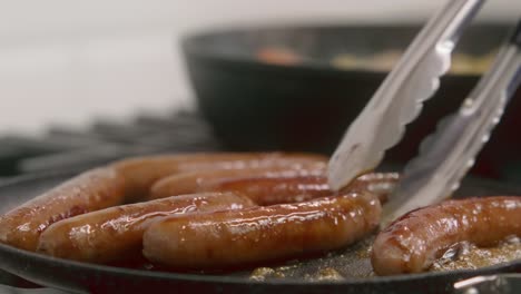 Frühstückswürste-Werden-Beim-Kochen-In-Einer-Gusseisernen-Pfanne-Vorsichtig-Gewendet