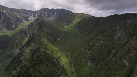 Lush-green-Tiganesti-Valley-under-cloudy-skies,-dramatic-mountain-scenery