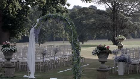 Arco-De-Boda-Al-Aire-Libre-Y-Filas-De-Sillas-En-Un-Ambiente-Pastoral.