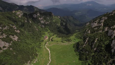 Aerial-shot-of-Malaiesti-Valley-in-the-lush-Bucegi-Mountains-with-a-winding-path