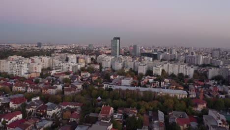 Bucharest-at-sunset-with-cityscape-and-glowing-skies,-wide-shot,-aerial-view