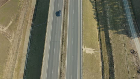 Elevated-shot-of-a-highway-with-a-singular-car-traveling-down-the-road
