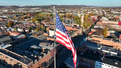 Aerial-view-of-York,-PA,-with-an-American-flag-in-the-foreground-and-historic-city-architecture-below