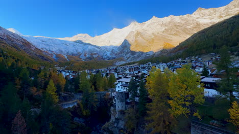 Früher-Morgen-Saas-Fee-Zermatt-Saastal-Erstes-Licht-Sonnig-Schweizer-Alpen-Berggipfel-Schattiges-Alpental-Chalet-Skiort-Stadt-Schweiz-Innenstadt-Fluss-Überquerung-Brücke-Langsamer-Schwenk-Nach-Links