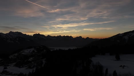 Drohne-Fliegt-über-Berge-Und-In-Der-Ferne-Hohe-Berge-Mit-Schnee-In-Amden,-Weesen,-Glarus,-Schweiz,-Sonnenaufgangswolken-Am-Himmel