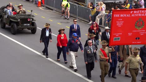 Representatives-of-the-4th-Battalion,-The-Royal-Australian-Regiment,-marching-down-the-street-during-Anzac-Day,-Brisbane,-Australia,-handheld-motion-close-up-shot