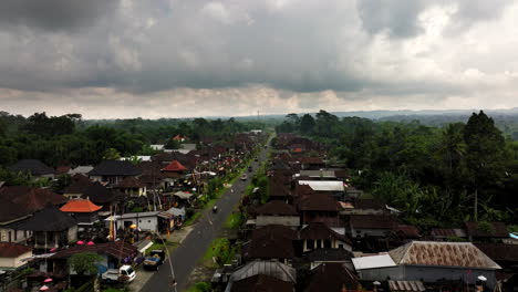 Stormy-sky-over-rural-Balinese-village-next-to-road-preparing-for-Nyepi,-aerial