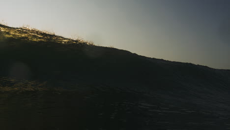 Frontal-view-from-ocean-water-surface-of-impact-zone-barrel-glistening-with-sunset-sky