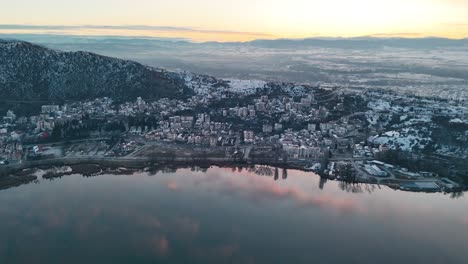 Eine-Drohnenaufnahme-Eines-Dorfbergs,-Warmes-Wetter,-Flug-über-Einen-Verträumten-Sonnenaufgang,-Der-Den-See-Widerspiegelt,-4K-Video,-Europäische-Frühlingsnatur,-Wunderschöne-Verschneite-Landschaft,-Malerische-Bunte-Wolken