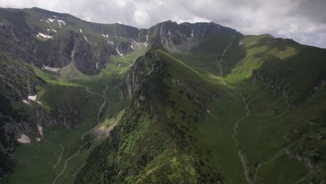 Exuberantes-Valles-Verdes-Ubicados-Entre-Los-Escarpados-Picos-De-Las-Montañas-De-Bucegi,-Bajo-Un-Cielo-Nublado.