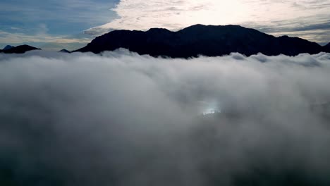 Majestic-mountain-peak-capped-with-snow,-piercing-through-a-sea-of-white-fluffy-clouds-on-a-cloudy-day-from-above-among-the-clouds