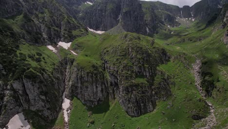 Verdant-Bucegi-Mountains,-lush-greenery,-rugged-cliffs,-aerial-shot,-summer