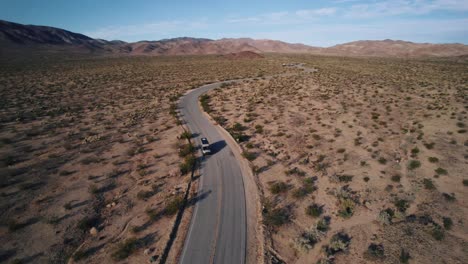 A-Mercedes-Sprinter-VAN-going-on-a-winding-road-in-Joshua-Tree-National-Park-while-a-drone-orbiting-around-it