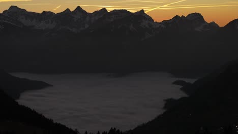 Drones-Que-Vuelan-Sobre-Las-Montañas-En-El-Valle-Son-Nubes-De-Niebla-Y-En-La-Distancia-Altas-Montañas-Con-Nieve-En-Amden,-Weesen,-Glarus,-Suiza,-Estado-De-ánimo-Del-Amanecer