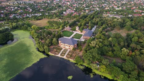 Palacio-Mogoșoaia-En-Rumania,-Exuberante-Vegetación,-Tranquilo-Lago-Al-Atardecer,-Vista-Aérea
