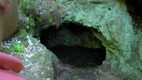 Pasando-Al-Turista-Parado-Frente-A-La-Entrada-De-La-Cueva,-Conocida-Como-La-Ubicación-Del-Santuario-De-La-Diosa-Guerrera-Egipcia-Bastet-En-La-Montaña-Strandzha-En-Bulgaria
