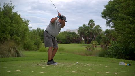 Slow-motion-of-an-over-weighted-latin-mexican-golfer-dressed-in-grey-hitting-the-ball-hard-with-an-iron