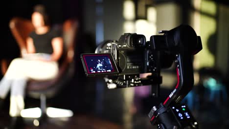 Person-with-advanced-video-production-equipment-approach-female-sit-on-egg-chair