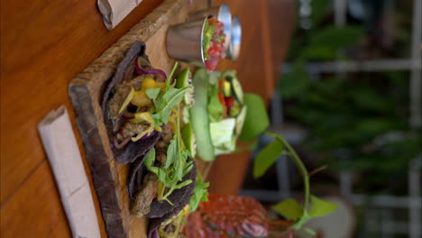 Vertical-slow-motion-close-up-of-mexican-beef-tacos-made-in-Yucatan-using-traditional-spices-called-recaudo-on-blue-corn-tortillas-and-red-onion