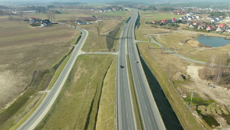 Luftaufnahme-Eines-Autobahnkreuzes-In-Ländlicher-Umgebung-Mit-Häusern-Und-Einem-Teich