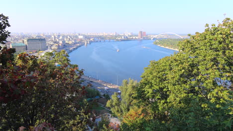 Beautiful-view-from-the-Glass-Bridge-on-the-famous-Dnipro-River-in-Kyiv-city-Ukraine,-buildings-and-trees-on-a-sunny-day,-4K-static-shot