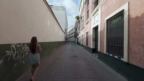 Beautiful-young-woman-walking-on-authentic-narrow-Spanish-side-street-Malaga-Spain