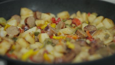 A-close-up-of-sausages,-peppers,-onions-and-potatoes-being-cooked-in-a-cast-iron-skillet