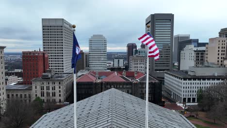 American-and-Virginia-flags-waving-atop-capitol-building-with-skyscraper-background-in-downtown-Richmond