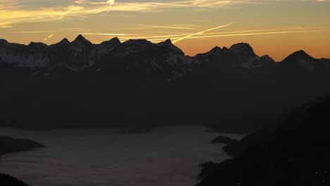 Drones-Que-Vuelan-Sobre-Las-Montañas-En-El-Valle-Son-Nubes-De-Niebla-Y-En-La-Distancia-Altas-Montañas-Con-Nieve-En-Amden,-Weesen,-Glarus,-Suiza,-Estado-De-ánimo-Del-Amanecer