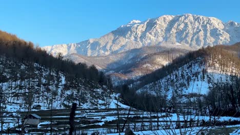 mountain-landscape-in-rural-life-countryside-village-in-Hyrcanian-forest-local-people-agriculture-is-rice-paddy-farm-field-forest-hills-covered-by-snow-and-sun-light-with-warm-temperature-in-sunset