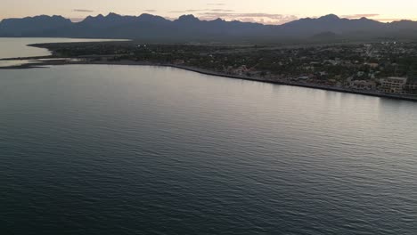 drone-fly-above-Loreto-Baja-California-Sur-Mexico-old-colonial-town-with-sea-gulf-ocean-and-mountains-desert-landscape-at-sunset