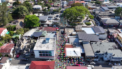 Aerial-birds-eye-shot-of-colorful-decorated-umbrella-over-street-in-Jarabacoa,-Dominican-Republic