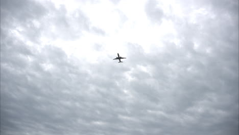 Airplane-aircraft-seen-from-below-flaying-through-a-cloudy-overcast-sky-on-a-chilly-day