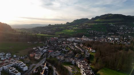 Aerial-view-of-swiss-small-Town-with-hill-and-neighborhood-at-sunset-time