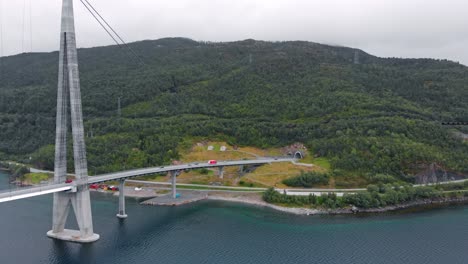 Aérea:-Puente-De-Hålogaland-Visto-Desde-El-Fiordo-De-Narvik-Y-Un-Tren-De-Mineral-Al-Fondo