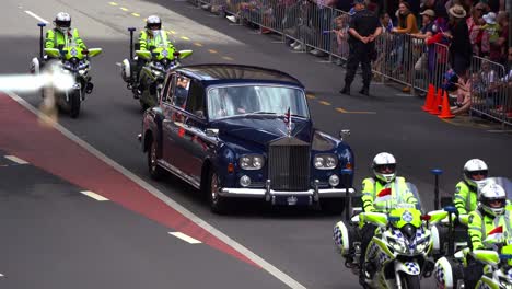 Das-Britische-Königsauto-Wird-Von-Polizisten-Auf-Motorrädern-Die-Adelaide-Street-Hinunter-Eskortiert,-Während-Menschenmengen-Die-Straße-Für-Die-Jährliche-Traditionelle-Anzac-Day-Parade-Säumen