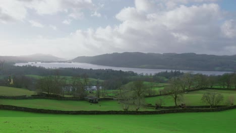 Drone-panning-from-the-right-to-the-left-side-of-the-frame,-showing-the-expanse-of-Windermere,-a-mountain-village-by-the-lake-at-Cumbria,-located-at-the-Lake-District-National-Park-in-Great-Britain