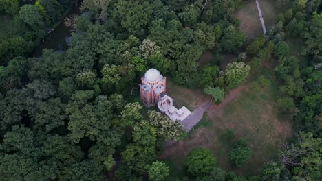 A-solitary-church-surrounded-by-lush-forests-at-dusk,-casting-a-serene-ambiance,-aerial-view