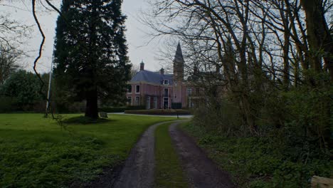 slow-cinematic-walkthrough-scenery-of-european-traditional-authentic-dutch-mansion-estate-house-castle-with-park,-nature,-trees-and-sunlight-by-smooth-slow-walking-on-the-path