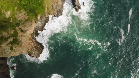 Bird's-eye-view-over-cliff's-edge-on-Oregon-Coast,-battered-by-Pacific-Ocean