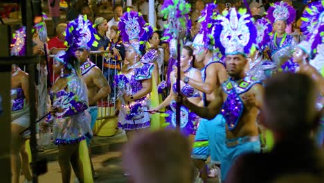 Silver-blue-costumed-Carnival-performers-parade-walking-down-street-at-night