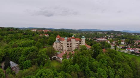 Castle-in-Baroque-and-Renaissance-style-on-forested-hill-romantic-aerial-view,-Poland