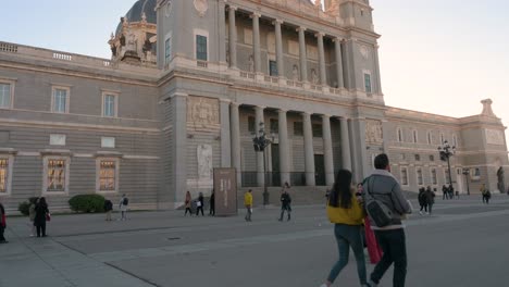 Tilt-shot-view-of-tourists-and-locals-taking-photos-and-walking-through-the-Armeria-plaza-in-front-of-the-Roman-Catholic-Almudena-Cathedral,-completed-and-consecrated-in-1993-by-Pope-John-Paul-II