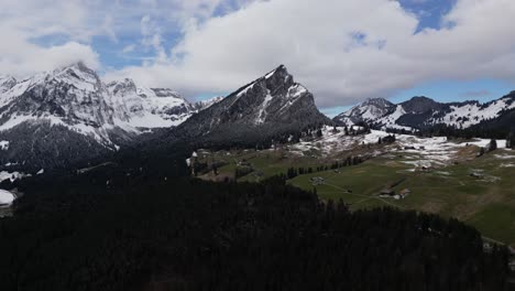 Perspectiva-Aérea-De-Los-Alpes-Suizos-Con-Picos-Nevados-Y-Casas-Dispersas-Enclavadas-En-Medio-Del-Paisaje,-Situadas-Cerca-De-Glaris,-Suiza