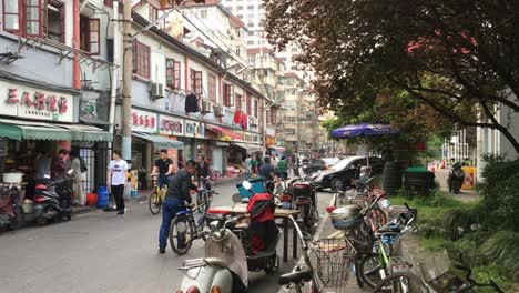 Belebte-Straße-In-Shanghai,-China-Mit-Vielen-Menschen,-Fahrrädern,-Motorrädern-Und-Menschen