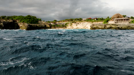 Choppy-azure-ocean-with-view-of-rocky-cove-of-Blue-Lagoon-Nusa-Ceningan,-aerial