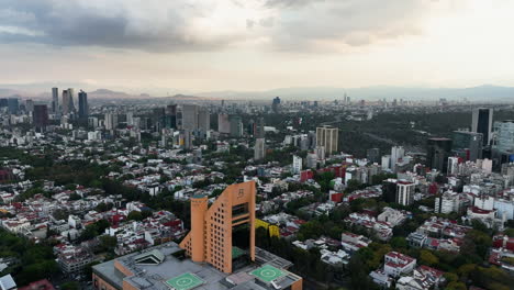 Aerial-view-backwards-over-the-El-Palacio-de-Hierro,-sunset-in-Polanco,-Mexico-city